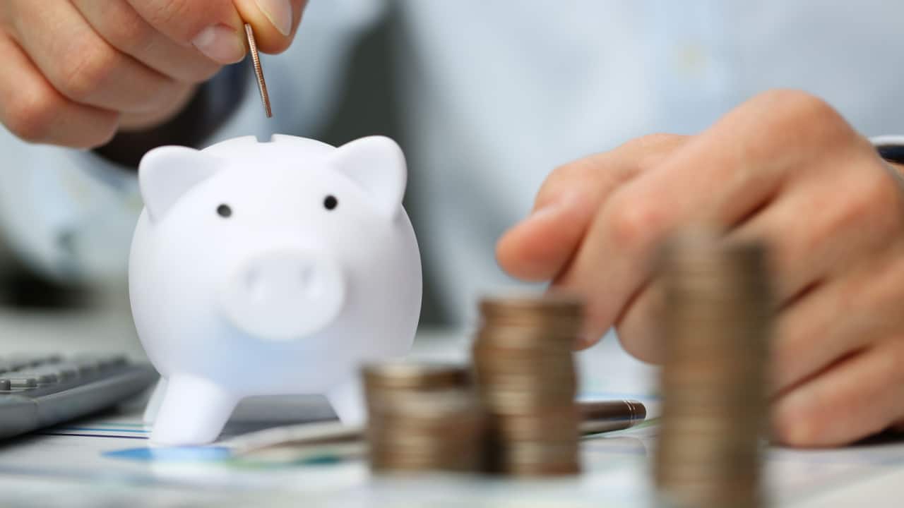 Hands organising money beside a savings jar